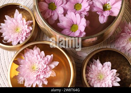 Ciotole tibetane con acqua e bellissimi fiori sul tavolo, piatti Foto Stock