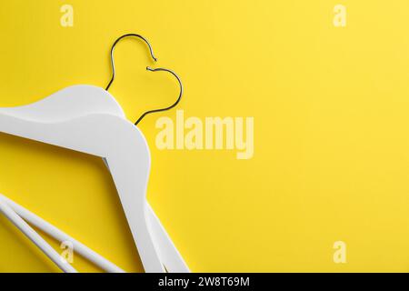 Appendiabiti bianchi su sfondo giallo, vista dall'alto. Spazio per il testo Foto Stock