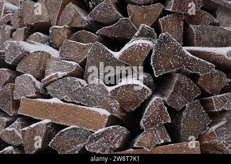 Legna da ardere impilata con neve e brace come sfondo, primo piano Foto Stock