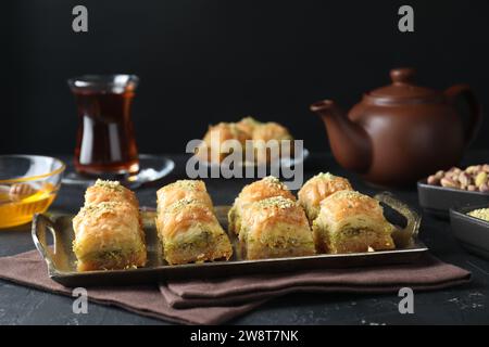 Delizioso baklava fresco con noci tritate servito su un tavolo con texture scura. Dolci orientali Foto Stock