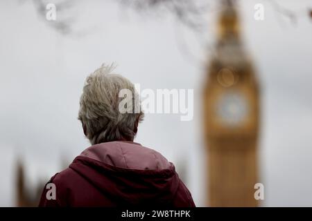 Londra, Regno Unito. 21 dicembre 2023. Una donna si trova vicino al Big Ben a Londra, in Gran Bretagna, 21 dicembre 2023, mentre Storm Pia porta forti venti in molte parti del Regno Unito e causa interruzioni dei trasporti in tutto il paese. Crediti: Li Ying/Xinhua/Alamy Live News Foto Stock