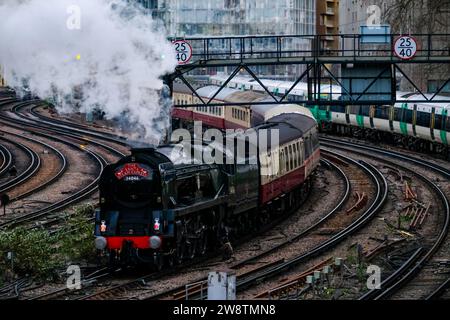 Londra, Regno Unito. 16 dicembre 2023. Il Santa Steam Express, un viaggio in treno a tema festivo popolare tra le famiglie, sfuma mentre parte da Victoria Station. Due servizi speciali - un treno a vapore e lussuose escursioni gastronomiche operate dalla Victoria Station di Londra in vista del Natale, dove passarono la Battersea Power Station, illuminata al tramonto in poi con un design festoso dell'artista David Hockney. Credito: Fotografia dell'undicesima ora/Alamy Live News Foto Stock