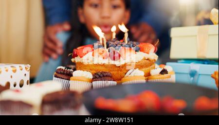 Buon compleanno, torta e lume di candela per festeggiare con la famiglia per feste, vacanze o giorni speciali a casa. Primo piano della bambina che soffia fiamma per Foto Stock