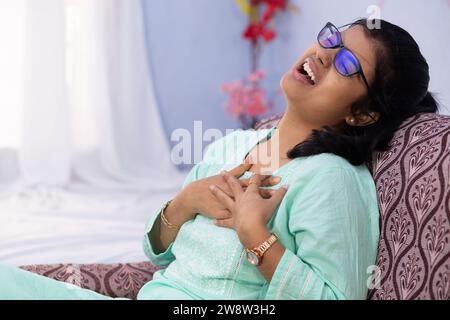 Una donna indiana che tiene il petto per il dolore, mostrando dolorosa espressione al chiuso Foto Stock
