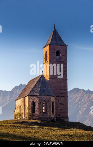 Hafling, Italia - la chiesa di montagna di San Catherine (Chiesa di Santa Caterina) nei pressi di Hafling - Avelengo su un caldo tramonto autunnale con il Dolo italiano Foto Stock