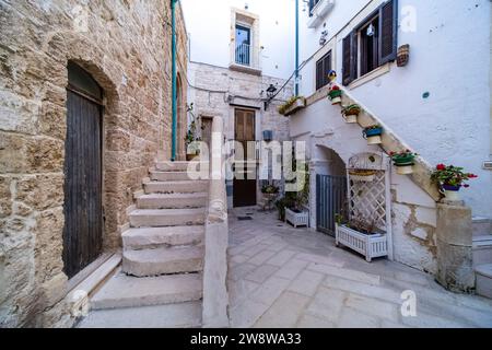 Scena di strada con un piccolo cortile tra case, scalinate e piante verdi in vaso. Foto Stock