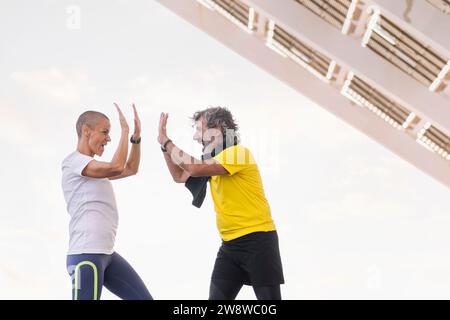 uomo anziano e allenatore sorridente felicemente alto cinque Foto Stock