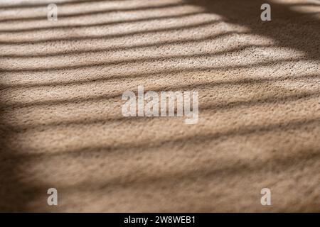 Sfondo marrone chiaro in tessuto morbido, primo piano. Velluto alla luce del sole attraverso le tende Foto Stock