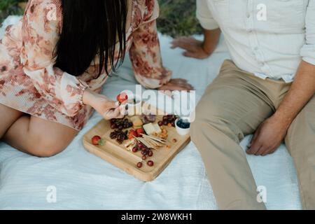 Coppia seduta a un picnic con un salumi Foto Stock