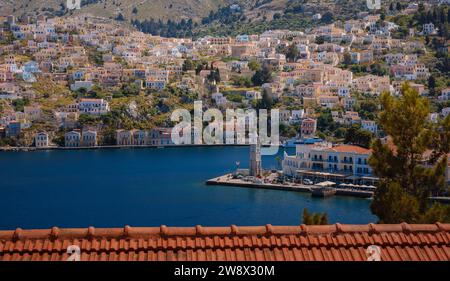 Isola di Symi, Grecia. Vacanze nelle isole della Grecia da Rodi nel Mar Egeo. Case colorate in stile neoclassico nella baia di Symi. Informazioni generali sui viaggi di vacanza. vista dalla collina Foto Stock