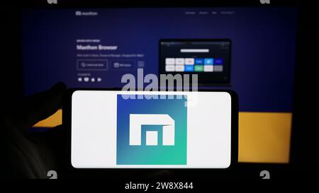 Persona che possiede uno smartphone con il logo della società di browser Web Maxthon davanti al sito Web. Concentrarsi sul display del telefono. Foto Stock