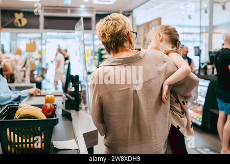 Nonna che porta con sé la nipote mentre si trova al banco del check-out del supermercato Foto Stock