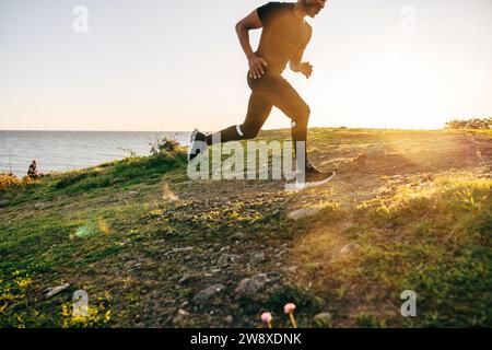Giovane che corre su una collina vicino al mare Foto Stock
