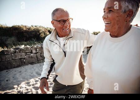 Felice coppia anziana che cammina insieme in spiaggia Foto Stock