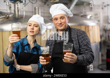 I produttori di birra interessati, maschi e femmine, che esaminano la qualità della birra in birrificio Foto Stock