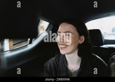 Donna sorridente seduta in auto in vacanza Foto Stock