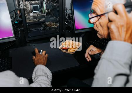 Amici anziani, donne e uomini, che giocano insieme al computer nella sala giochi durante il fine settimana Foto Stock