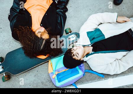 Amici multirazziali maschili e femminili sdraiati per strada Foto Stock