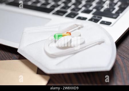 Immagine di un computer portatile, una carta d'oro, pillole e dispositivi di protezione contro il coronavirus. Concetto di assicurazione sanitaria. La medicina. Supporti misti Foto Stock