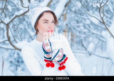 Ritratto di una ragazza affascinante che tiene in mano una tazza di bevanda calda. Concetto di Natale, feste invernali, passeggiate nei boschi, vacanze. Foto Stock