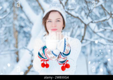 Ritratto di una ragazza affascinante che tiene in mano una tazza di bevanda calda. Concetto di Natale, feste invernali, passeggiate nei boschi, vacanze. Foto Stock