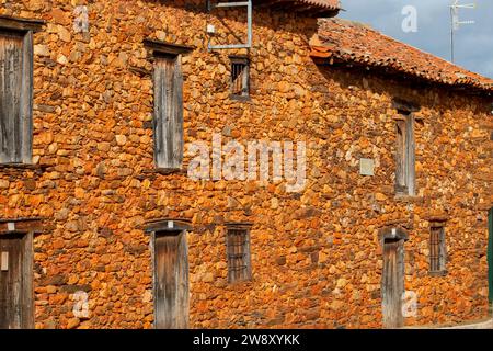 Case, finestre e facciate costruite con pietra calcarea rossa tipica della regione di la Maraguatería a Castilla y León, Spagna Foto Stock