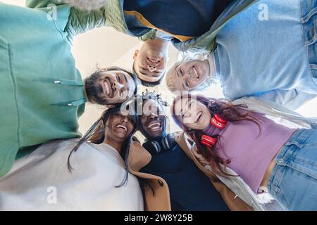 Vista dall'alto di un gruppo eterogeneo di amici gioiosi che formano un cerchio, simboleggiando l'unità e l'amicizia. Foto Stock