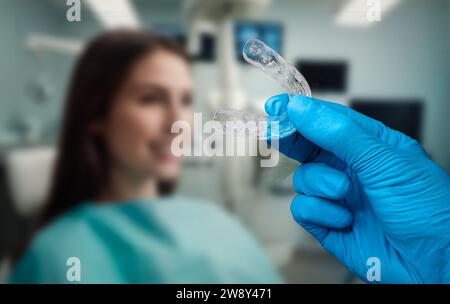 vista della mano di un medico che tiene un fermo dentale e sfondo sfocato di una donna irriconoscibile seduta sulla sedia dentista Foto Stock