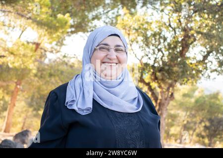 donna musulmana di mezza età che indossa hijab che guarda la macchina fotografica e sorride come ritratto per una donna Foto Stock