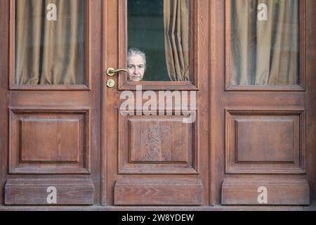 Tiflis, Georgia. 22 ottobre 2023. Una donna siede dietro una porta di legno e guarda fuori sulla strada. Credito: Sebastian Kahnert/dpa/Alamy Live News Foto Stock