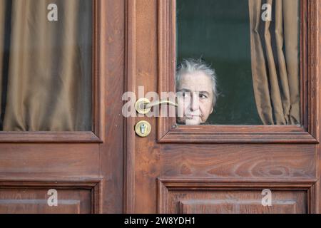 Tiflis, Georgia. 22 ottobre 2023. Una donna siede dietro una porta di legno e guarda fuori sulla strada. Credito: Sebastian Kahnert/dpa/Alamy Live News Foto Stock