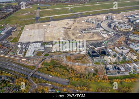 Vista aerea, aeroporto di Düsseldorf, porta 1 e cantiere, terminal aerei e sala ricevimento, circondati da alberi decidui autunnali, Unterrat Foto Stock