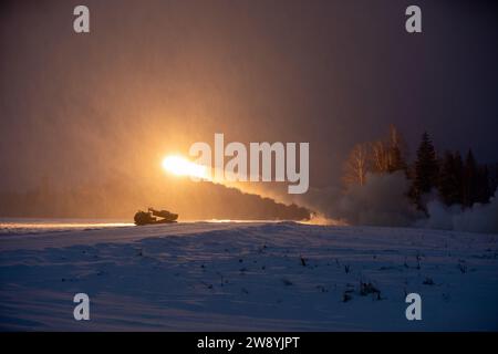 Soldati dell'esercito degli Stati Uniti assegnati alla Task Force Voit, 3rd Battalion, 27th Field Artillery Regiment, 18th Field Artillery Brigade, 18th Airborne Corps, supporto della 3rd Infantry Division, dimostrare il M142 High-Mobility Artillery Rocket System (HIMARS) alle truppe multinazionali del gruppo di combattimento avanzato della NATO Estonia durante un'esercitazione di fuoco vivo presso il Central Training Area​​ vicino a Camp tapa, Estonia, 22 dicembre 2023. La missione della 3rd Infantry Division in Europa è quella di impegnarsi in formazione ed esercitazioni multinazionali in tutto il continente, lavorando a fianco degli Alleati della NATO e del securit regionale Foto Stock