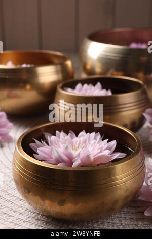 Ciotole tibetane con acqua e bellissimi fiori sul tavolo, primo piano Foto Stock