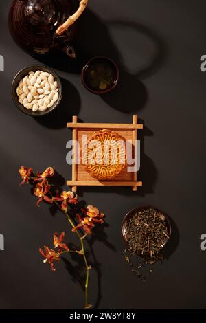 Scena pubblicitaria per una torta tradizionale tipica del Mid-Autumn Festival. Una torta di luna su vassoio con fiori, semi di zucca e set di tè decorato Foto Stock