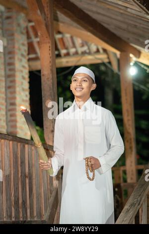 Bell'uomo islamico con abito musulmano bianco nella notte buia del villaggio Foto Stock