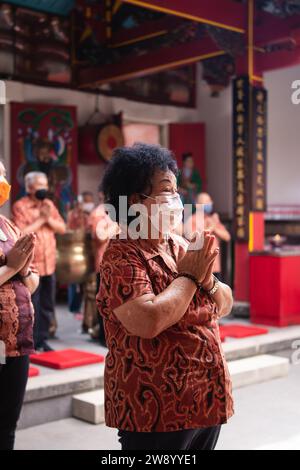 Bandung, Indonesia - 8 gennaio 2022: Il visitatore che prega insieme ai monaci di fronte alle offerte al dio al tempio del Buddha Foto Stock