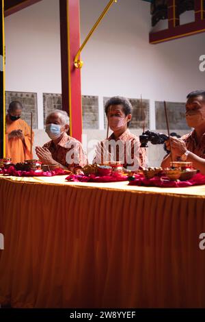 Bandung, Indonesia - 8 gennaio 2022: Il visitatore che prega insieme ai monaci di fronte alle offerte al dio al tempio del Buddha Foto Stock