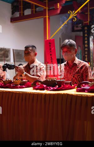 Bandung, Indonesia - 8 gennaio 2022: Il visitatore che prega insieme ai monaci di fronte alle offerte al dio al tempio del Buddha Foto Stock