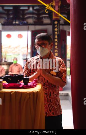 Bandung, Indonesia - 8 gennaio 2022: Il visitatore che prega insieme ai monaci di fronte alle offerte al dio al tempio del Buddha Foto Stock