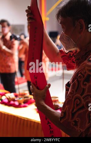 Bandung, Indonesia - 8 gennaio 2022: Il vecchio porta le offerte all'altare mentre prega con i monaci all'interno del tempio del Buddha Foto Stock