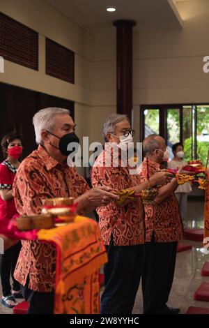 Bandung, Indonesia - 8 gennaio 2022: Il vecchio porta le offerte all'altare mentre prega con i monaci all'interno del tempio del Buddha Foto Stock