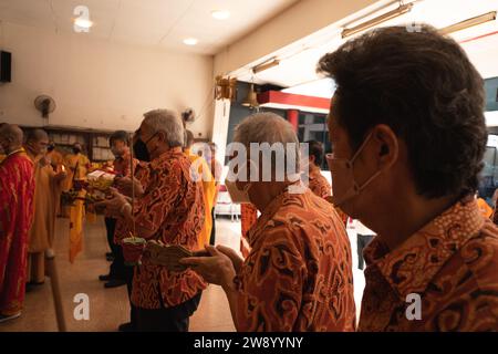 Bandung, Indonesia - 8 gennaio 2022: Il vecchio porta le offerte all'altare mentre prega con i monaci all'interno del tempio del Buddha Foto Stock