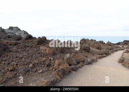 Sentiero escursionistico a Los Hervideros. Costa sud-occidentale, aspro paesaggio vulcanico, grotte e colline di lava rossa. Lanzarote, Isole Canarie, Spagna Foto Stock