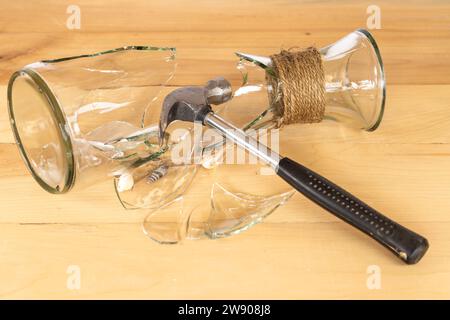 Vaso di vetro rotto con un martello di metallo Foto Stock