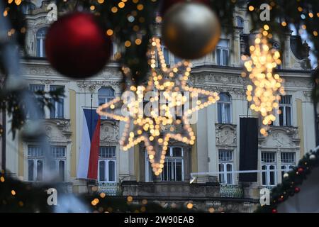 Praga, Repubblica Ceca. 23 dicembre 2023. Una bandiera ceca (sinistra) e nera al Palazzo Kinsky, appartenente alla Galleria Nazionale di Praga, nella Piazza della città Vecchia di Praga, Repubblica Ceca, il 23 dicembre, dove si tiene il mercato di Natale, il giorno del lutto di Stato per commemorare le vittime di un uomo armato che ha ucciso 14 persone e ferito altre 25 alla Facoltà di Arti della Charles University il 21 dicembre. Crediti: Michal Kamaryt/CTK Photo/Alamy Live News Foto Stock