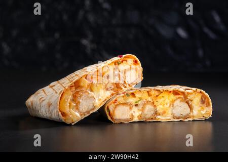 Tacos francesi con popcorn di pollo. Taglia i Tacos francesi da vicino su sfondo nero. Delizioso sandwich di taaco francese, fast food, cibo buono e straordinario Foto Stock