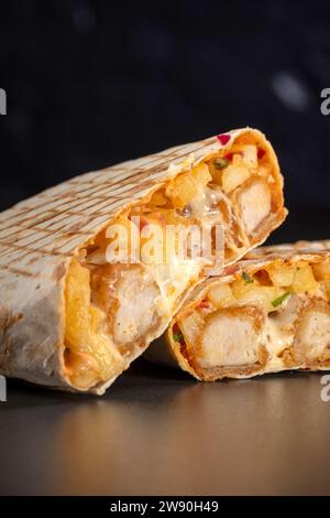 Tacos francesi con popcorn di pollo. Taglia i Tacos francesi da vicino su sfondo nero. Delizioso sandwich di taaco francese, fast food, cibo buono e straordinario Foto Stock