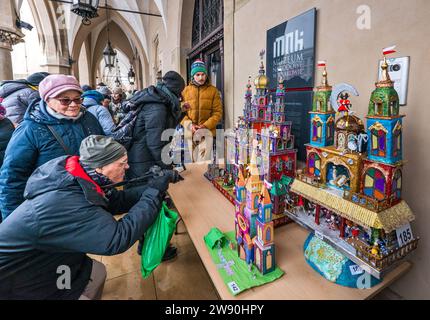 Persone che scattano foto di Szopki (presepi di Natale) all'apertura del concorso annuale a dicembre, evento incluso nella lista dei patrimoni culturali dell'UNESCO, nei portici di Sukiennice (sala dei tessuti), Piazza del mercato principale, Kraków, Polonia Foto Stock