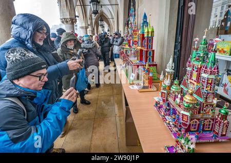 Persone che scattano foto di Szopki (presepi di Natale) all'apertura del concorso annuale a dicembre, evento incluso nella lista dei patrimoni culturali dell'UNESCO, nei portici di Sukiennice (sala dei tessuti), Piazza del mercato principale, Kraków, Polonia Foto Stock